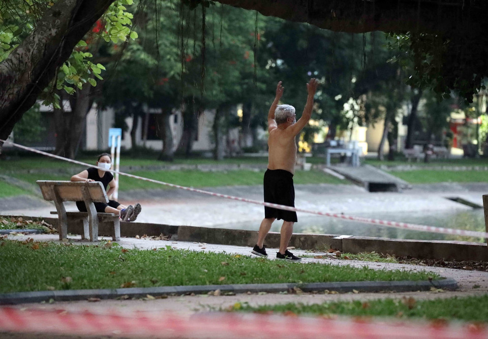 Vượt qua rào chặn để vào tập thể dục tại hồ Thiền Quang lúc 5h sáng 26/7. (Ảnh: Nhật Anh/TTXVN)