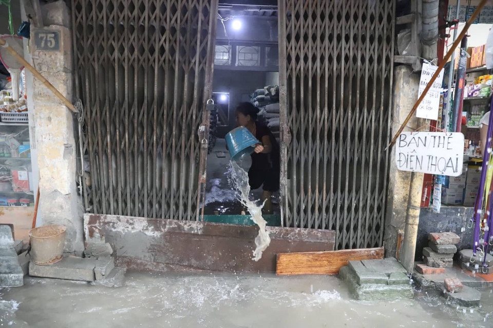 Một vài người dân phải che chắn, tát nước để tránh nước tràn vào nhà. (Ảnh: PV/Vietnam+) 