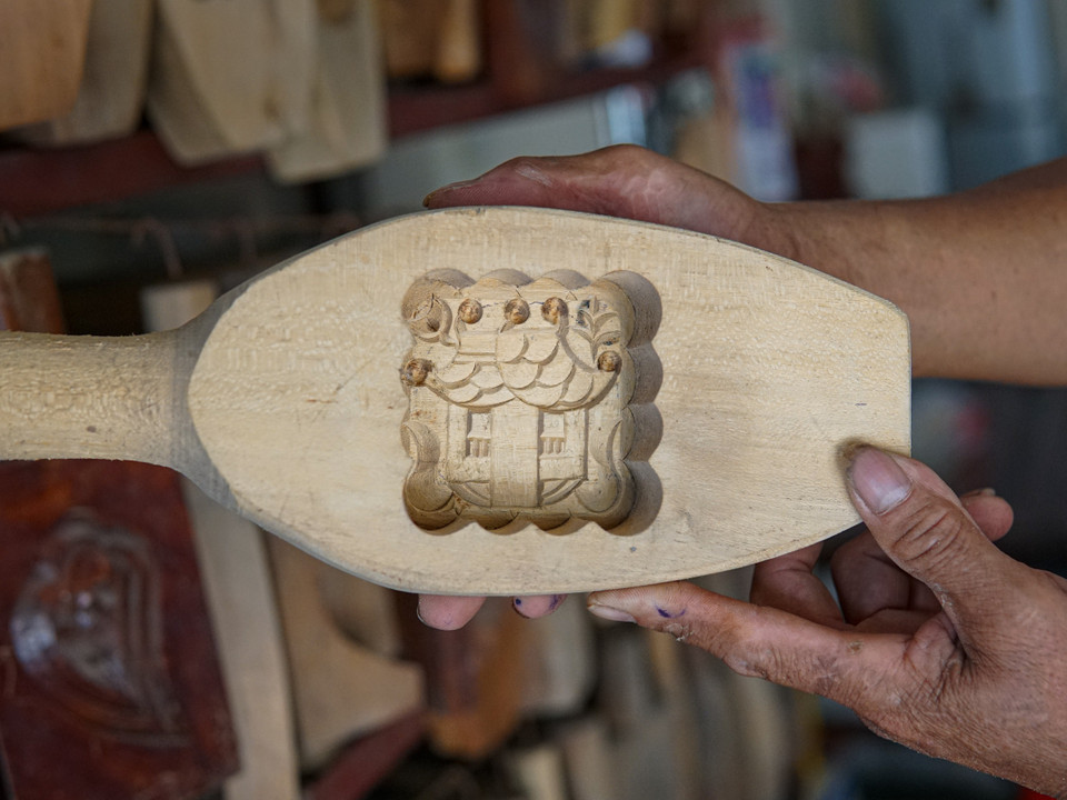 Ông Bản giới thiệu khuôn bánh hình Chùa Một Cột. Đây là một trong số nhiều mẫu phức tạp mà ông phải tốn nhiều giờ đồng hồ đục, đẽo mới có thể làm ra. (Ảnh: Minh Hiếu/Vietnam+)