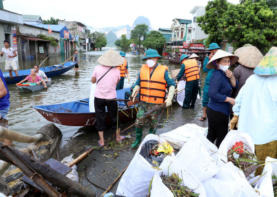 Cán bộ chiến sỹ, Lực lượng vũ trang Bộ Chỉ huy Quân sự tỉnh Hà Nam và dân quân tự vệ cùng người dân tham gia thu gom rác thải tại điểm ngập lụt Thị trấn Kiện Khê huyện Thanh Liêm. (Ảnh: Đại Nghĩa/TTXVN)