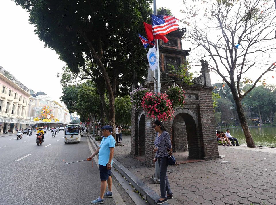 Cờ Mỹ, cờ Triều Tiên và cờ Việt Nam, bên dưới là biểu tượng hai bàn tay bắt chặt vào nhau thể hiện tinh thần của cuộc gặp lớn, được treo quanh hồ Hoàn Kiếm. (Ảnh: Danh Lam/TTXVN)