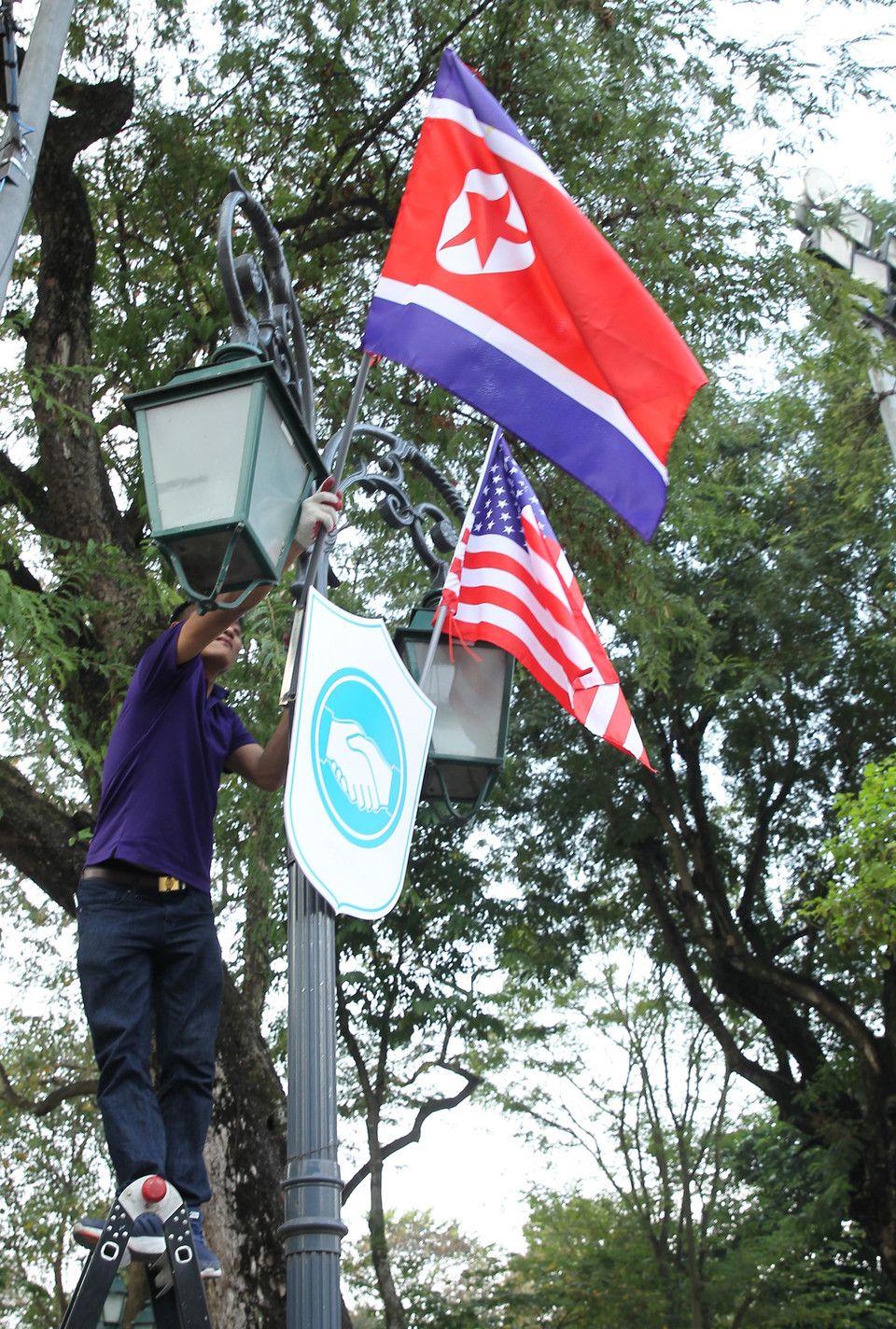 Cờ Mỹ và cờ Triều Tiên, bên dưới là biểu tượng hai bàn tay bắt chặt vào nhau thể hiện tinh thần của cuộc gặp lớn, được treo bên ngoài Nhà khách Chính phủ trên phố Ngô Quyền, quận Hoàn Kiếm. (Ảnh: Lâm Khánh/TTXVN)