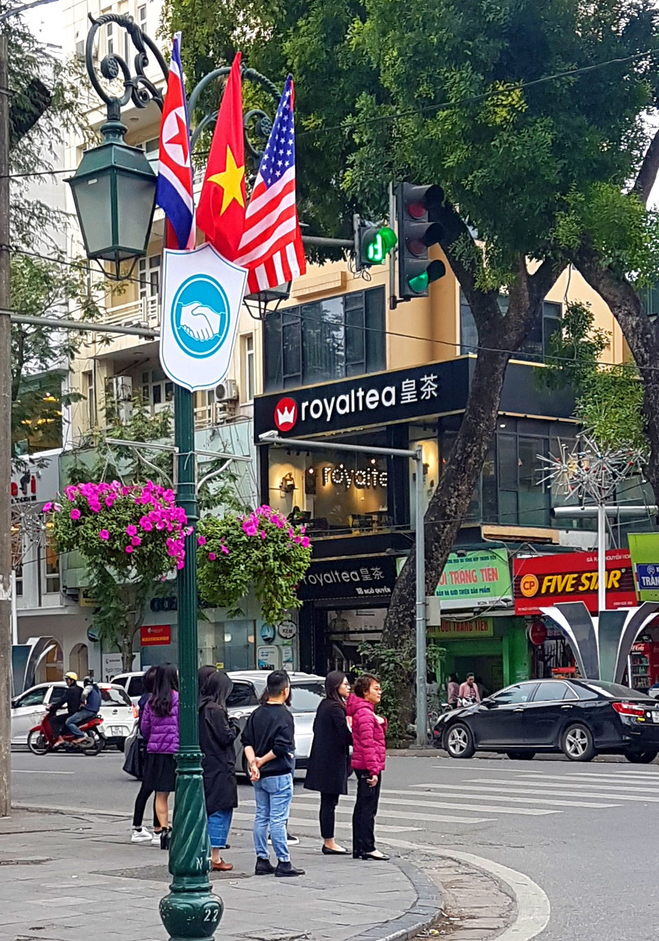 Cờ Mỹ, cờ Triều Tiên và cờ Việt Nam, bên dưới là biểu tượng hai bàn tay bắt chặt vào nhau thể hiện tinh thần của cuộc gặp lớn, được treo trên phố Ngô Quyền. (Ảnh: Ngọc Hà/TTXVN)