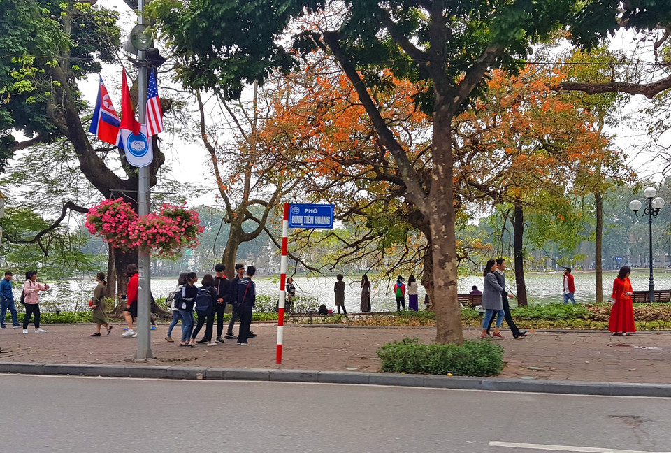 Cờ Mỹ, cờ Triều Tiên và cờ Việt Nam, bên dưới là biểu tượng hai bàn tay bắt chặt vào nhau thể hiện tinh thần của cuộc gặp lớn, được treo trên phố Đinh Tiên Hoàng, quang hồ Hoàn Kiếm. (Ảnh: Ngọc Hà/TTXVN)