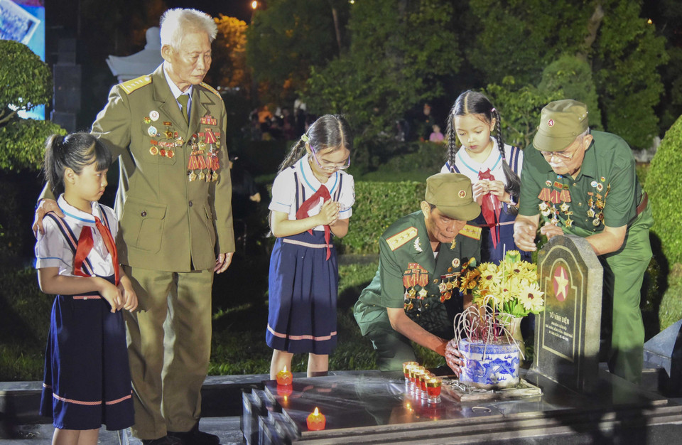 Các cựu chiến binh Điện Biên và các cháu thiếu nhi thắp hương lên các phần mộ liệt sỹ tại Nghĩa trang A1-Điện Biên. (Ảnh: Xuân Tư/TTXVN)