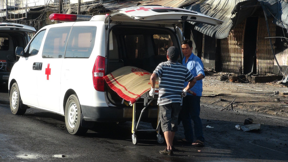 Lực lượng chức năng đưa thi thể nạn nhân ra khỏi hiện trường vụ cháy. (Ảnh: Đậu Tất Thành/TTXVN)