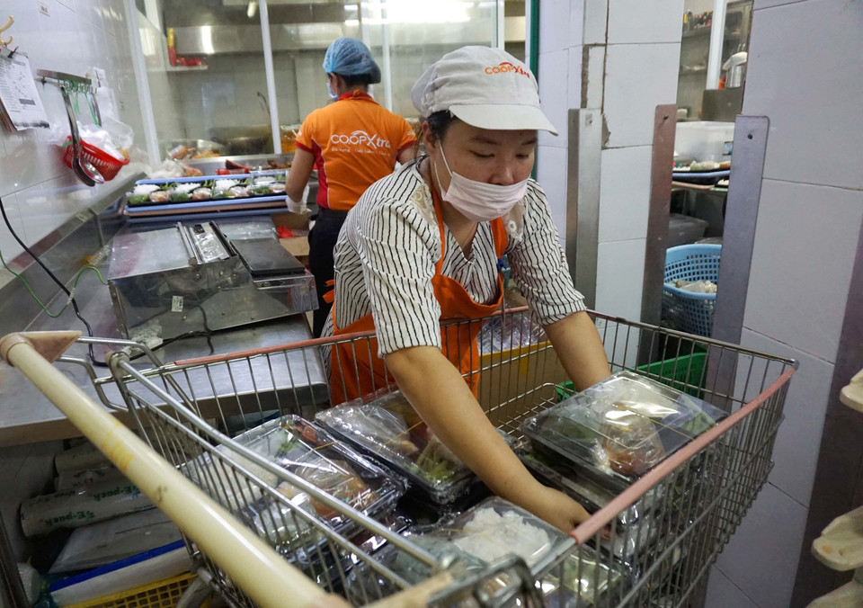 Mỗi suất ăn được nhân viên Sài Gòn Co.op cho vào hộp và đóng gói cẩn thận trước khi chuyển đến phục vụ người dân trong khu cách ly. (Ảnh: Thanh Vũ-Tuyết Thư/TTXVN)
