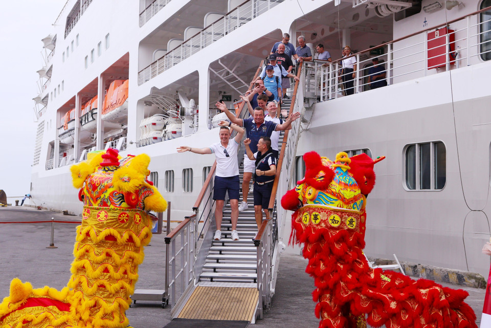 Du khách hào hứng với màn múa lân chào đón khi vừa xuống tàu. (Ảnh: Trần Lê Lâm/TTXVN)