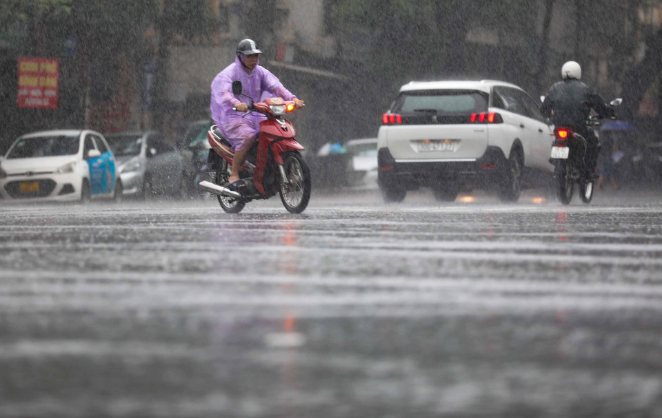 Người dân di chuyển dưới những đợt mưa liên tục trong sáng 11/8. (Ảnh: Thanh Tùng/TTXVN)