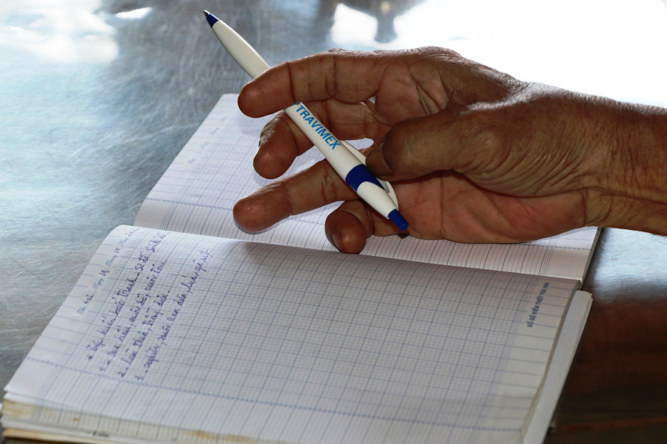 Lão nông cẩn trọng ghi lại từng nội dung thảo luận tại nhóm các thành viên nam.(Ảnh: PV/Vietnam+)