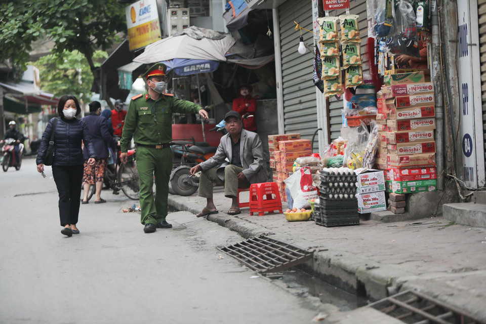 Công an phường Vĩnh Tuy (Hai Bà Trưng) nhắc nhở người dân, hộ kinh doanh thực hiện đúng chỉ thị của Thủ tướng Chính phủ. (Ảnh: Thanh Tùng/TTXVN)