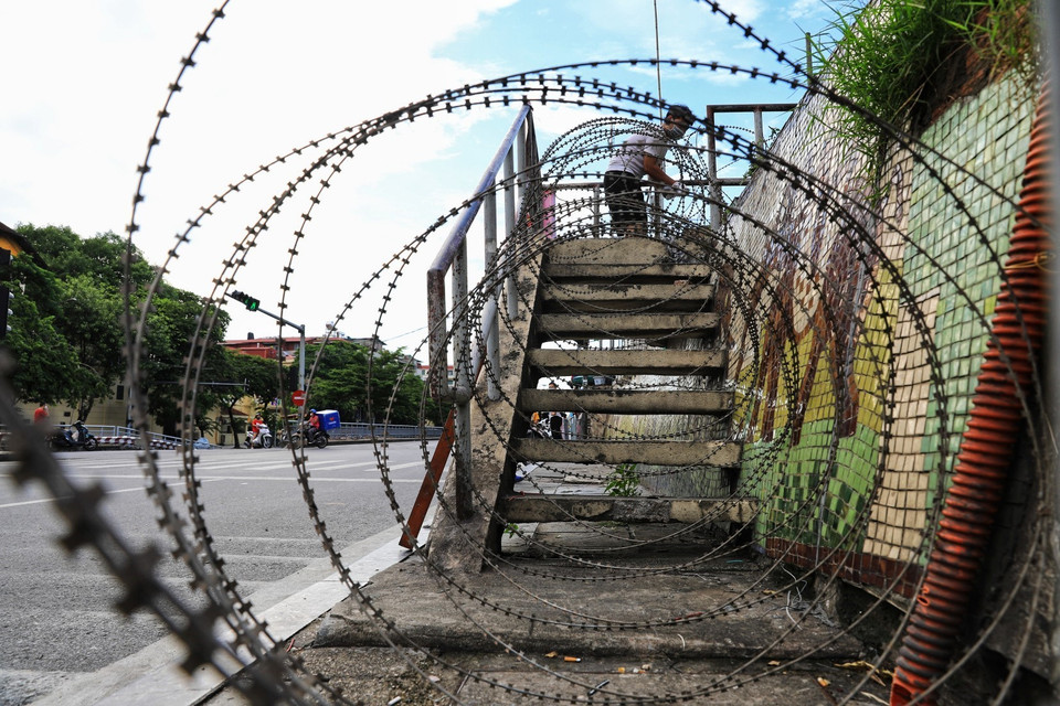 Tại mỗi đoạn cầu thang lên xuống thông ra ngoài đê, lực lượng lượng quân đội quận Hoàn Kiếm lắp hàng rào dây thép gai tránh tình trạng người dân có thể trèo tường ra ngoài hay chuyển đồ ra cho người thân. (Ảnh: Thành Đạt/TTXVN)