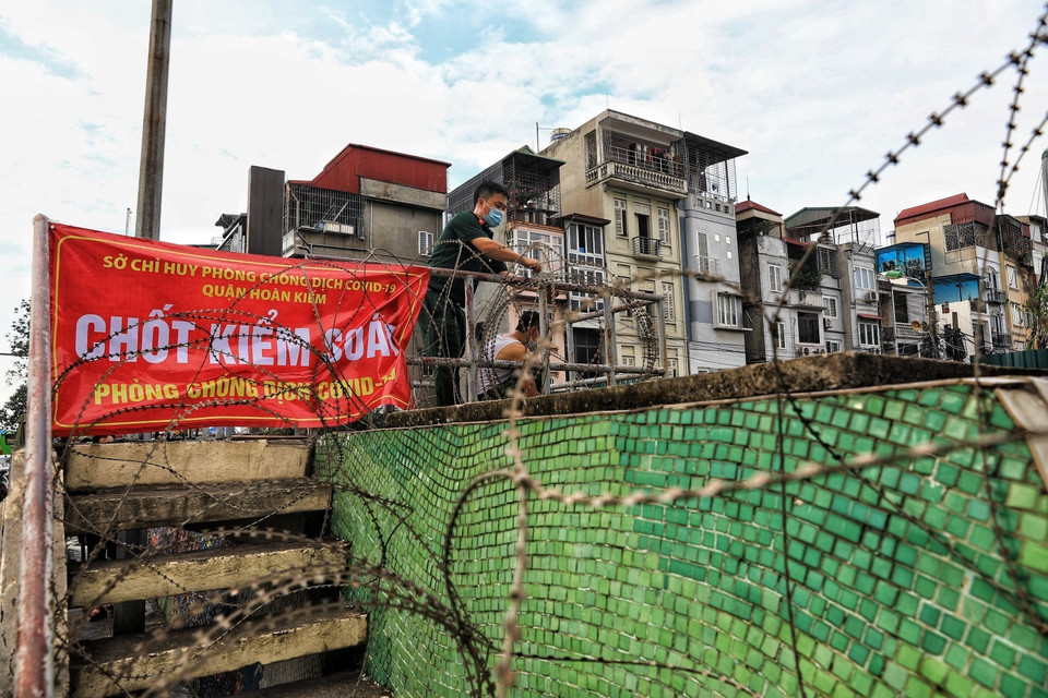 Tại mỗi đoạn cầu thang lên xuống thống ra ngoài đê, lực lượng lượng quân đội quận Hoàn Kiếm lắp hàng rào dây thép gai tránh tình trạng người dân có thể trèo tường ra ngoài hay chuyển đồ ra cho người thân. (Ảnh: Thành Đạt/TTXVN)