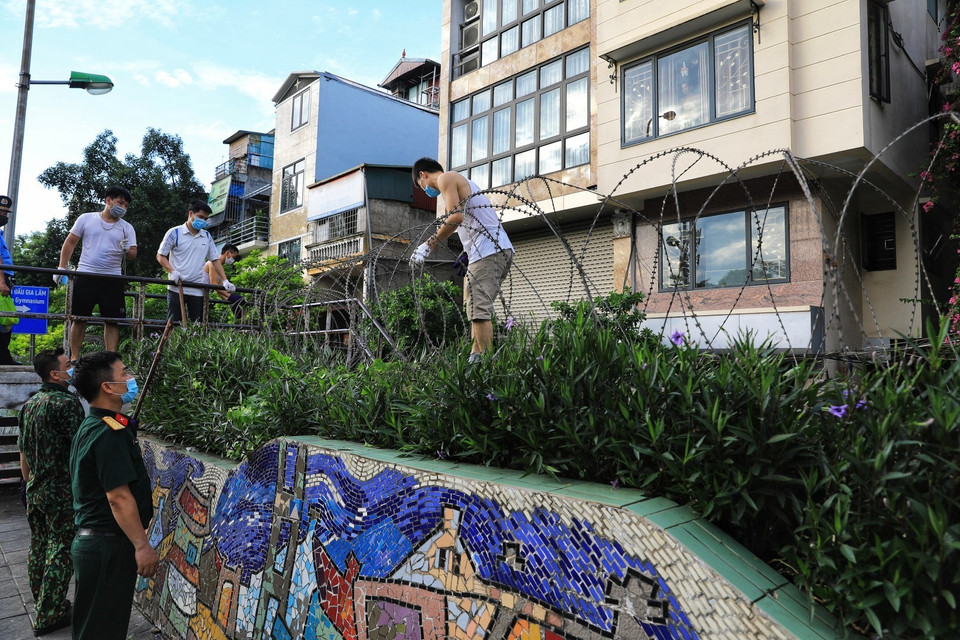 Tại mỗi đoạn cầu thang lên xuống thông ra ngoài đê, lực lượng lượng quân đội quận Hoàn Kiếm lắp hàng rào dây thép gai tránh tình trạng người dân có thể trèo tường ra ngoài hay chuyển đồ ra cho người thân. (Ảnh: Thành Đạt/TTXVN)