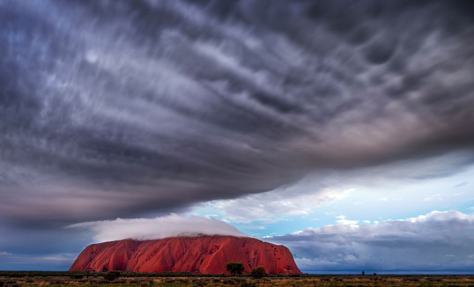 Di sản thế giới Ayers Rock ở Australia. (Nguồn: NatGeo) Nhiếp ảnh gia đã ghi lại khoảnh khắc độc đáo khi những đám mây đen sà xuống thấp như ôm trọn di sản này.