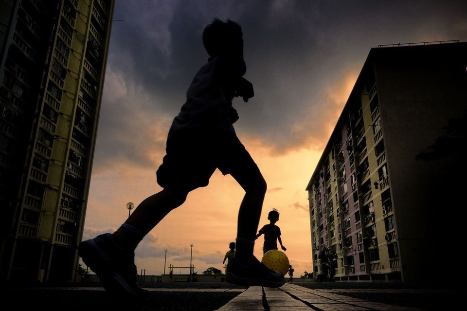 Khoảnh khắc vui vẻ dưới ánh hoàng hôn. (Nguồn: NatGeo) Những em nhỏ vui vẻ đá bóng trên sân của một khu chung cư ở Hong Kong.