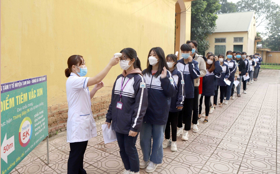 Học sinh được kiểm tra thân nhiệt trước khi tiêm, tại điểm tiêm Trường THPT Tam Đảo 1, huyện Tam Đảo. (Ảnh: Hoàng Hùng/TTXVN)