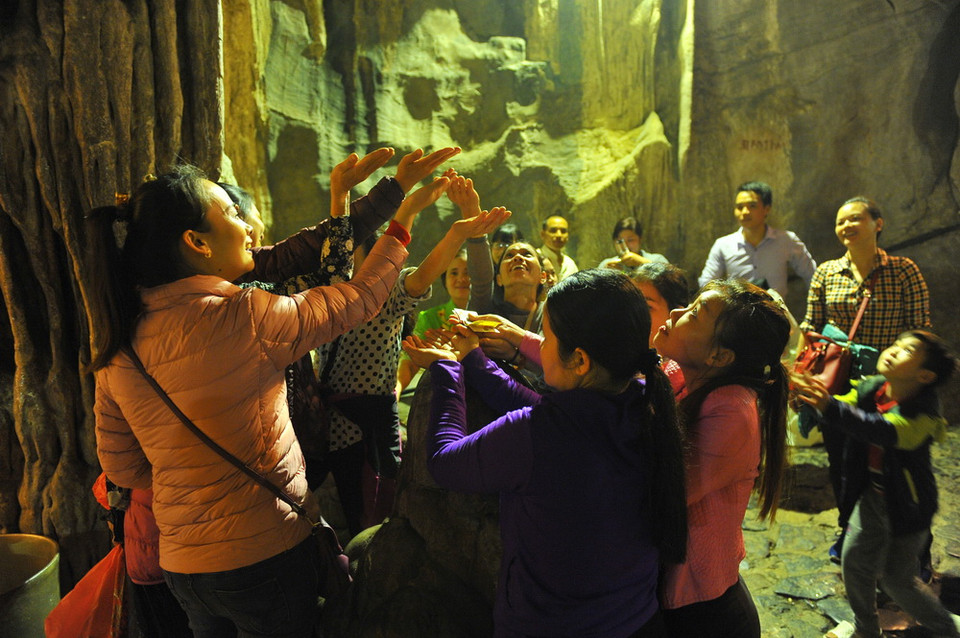 Các du khách đón những giọt nước từ nhũ đá trong động Hương Tích để cầu mong một năm mới nhiều sức khỏe, an lành và hạnh phúc. (Ảnh: Minh Đức/TTXVN)