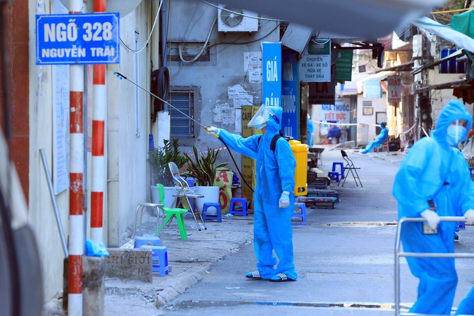 Nhân viên y tế phun khử khuẩn tại ngõ 328 Nguyễn Trãi, phường Thanh Xuân Trung, sau khi đưa các ca F1 đi cách ly tập trung. (Ảnh: Tuấn Anh/TTXVN)
