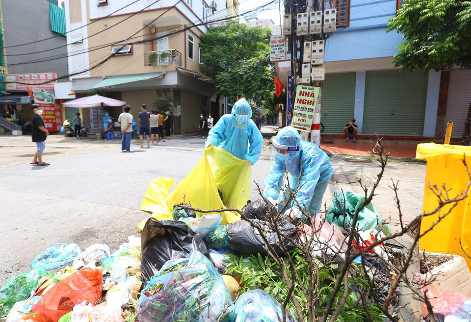 Những công nhân môi trường làm việc trong khu vực phong tỏa luôn phải hết sức chú ý phòng dịch vì có nguy cơ lây nhiễm cao. (Ảnh: Hoàng Hiếu/TTXVN)