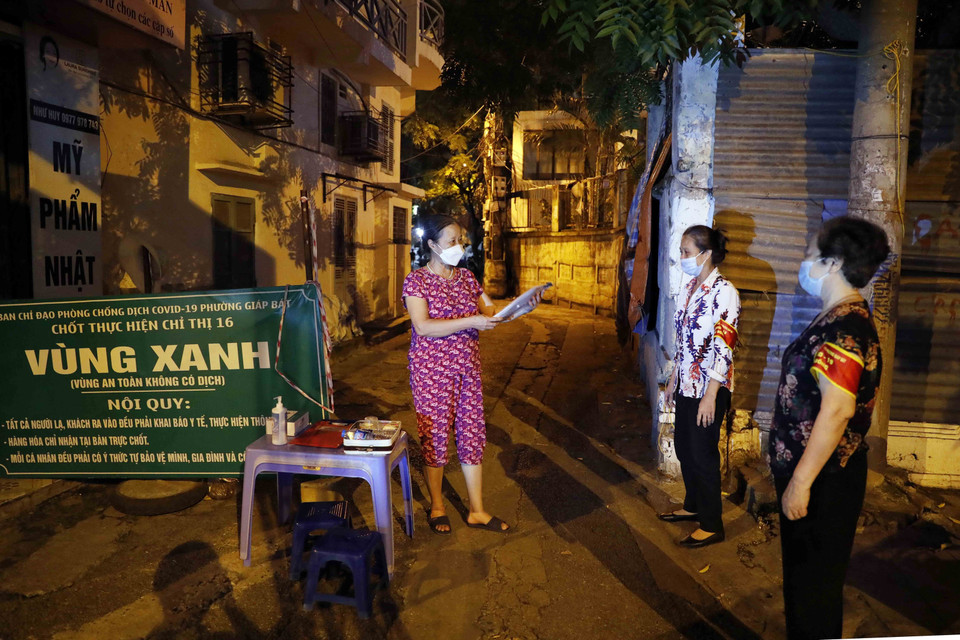 Tổ trưởng tổ dân cư số 6, phường Giáp Bát, quận Hoàng Mai, đi kiểm tra việc trực chốt vùng xanh trong đêm. (Ảnh: Trần Việt/TTXVN)