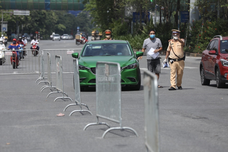 Lực lượng chức năng lập hàng rào phân luồng phương tiện, kiểm soát chặt người và phương tiện khi ra đường. (Ảnh: Minh Quyết/TTXVN)