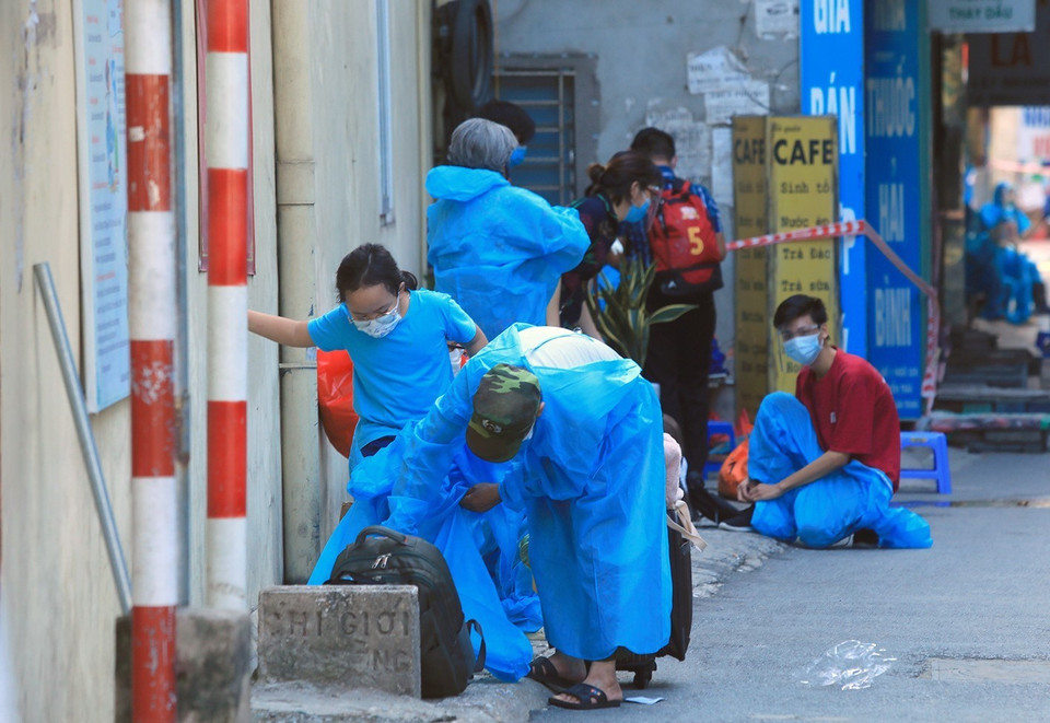 Các trường hợp F1 tại ngõ 328 Nguyễn Trãi, phường Thanh Xuân Trung, mặc đồ bảo hộ trước khi được đưa đi cách ly tập trung. (Ảnh: Tuấn Anh/TTXVN)