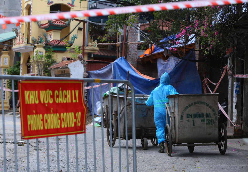 Công nhân môi trường đi vào khu vực phong tỏa làm nhiệm vụ. (Ảnh: Hoàng Hiếu/TTXVN)