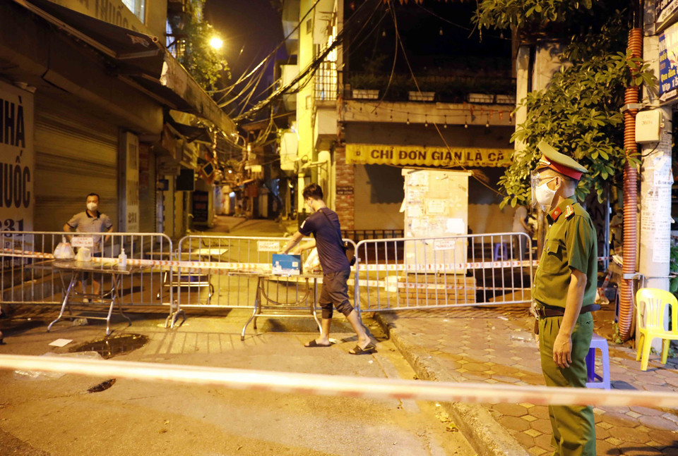 Công an hướng dẫn người tiếp tế hàng tại khu cách ly ở ngõ 24, phố Kim Đồng, phường Giáp Bát. (Ảnh: Trần Việt/TTXVN)