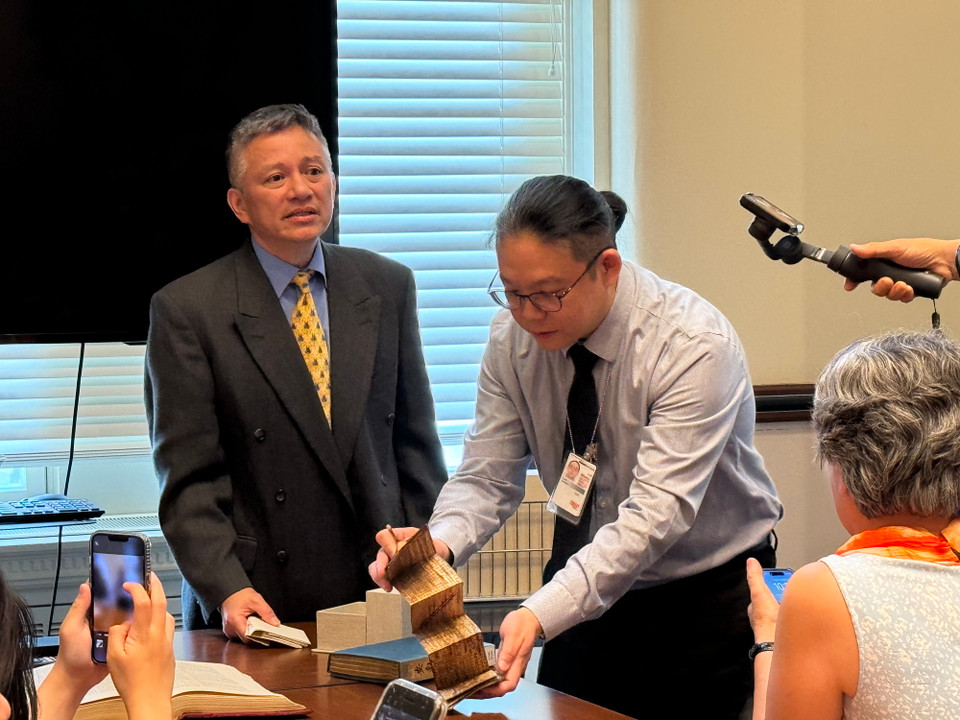 Nhân viên Thư viện giới thiệu với khách tham quan cuốn sách cổ của người Malaysia được làm từ xương bò và lá cây. (Ảnh: Kiều Trang/Vietnam+)