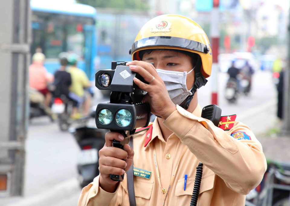 Cán bộ, chiến sỹ Đội cảnh sát giao thông số 14 bắn tốc độ với các trường hợp xe khách chạy 'rùa bò.' (Ảnh: Phạm Kiên/TTXVN)