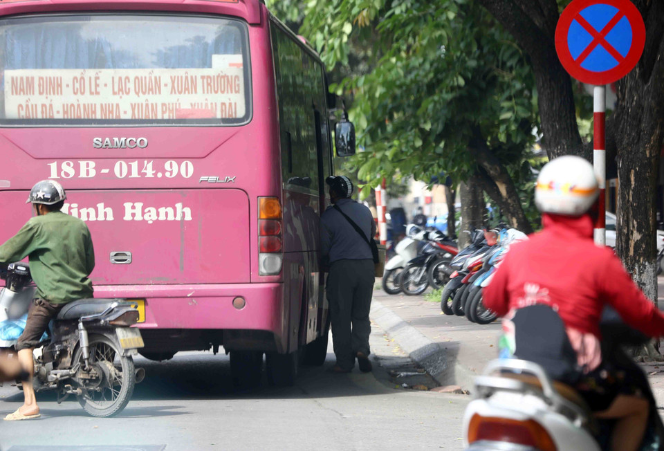 Dù đã có biển báo cấm dừng, cấm đỗ nhưng nhiều trường hợp xe khách vẫn cố tình dừng đỗ đón, trả khách sai quy định tại tuyến đường Giải Phóng. (Ảnh: Phạm Kiên/TTXVN)