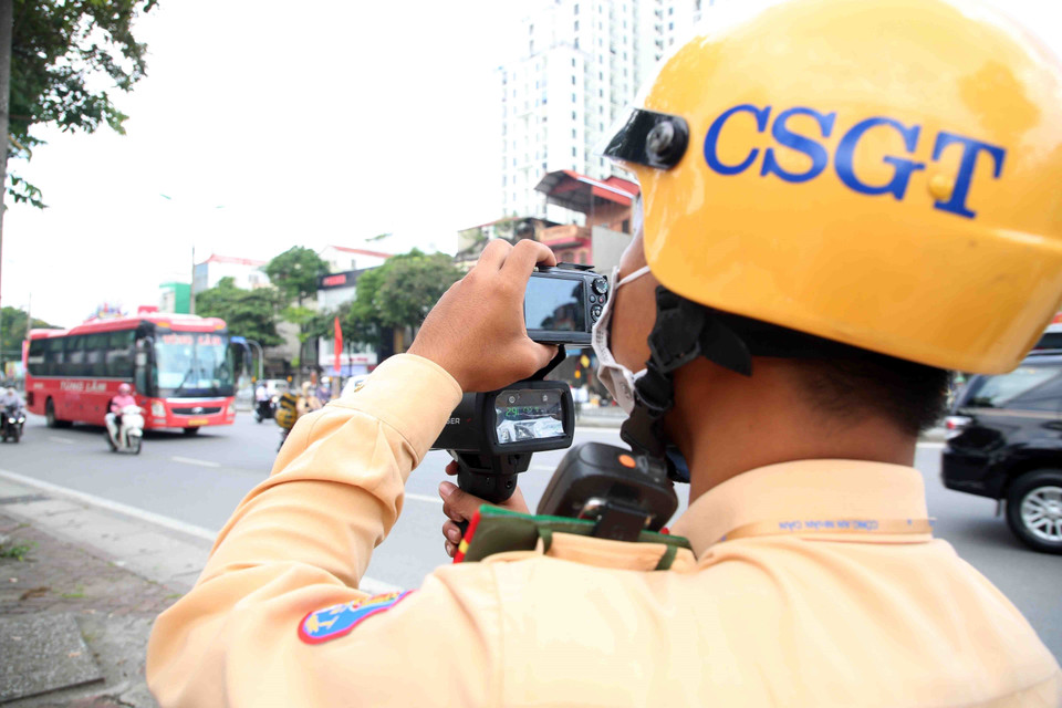 Cán bộ, chiến sỹ Đội cảnh sát giao thông số 14 (Công an thành phố Hà Nội) tiến hành bắn tốc độ với các trường hợp xe khách chạy 'rùa bò' trên đường Giải Phóng. (Ảnh: Phạm Kiên/TTXVN)