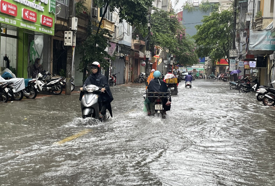 Mưa lớn gây ngập úng đến hết cả bánh xe máy trên con đường Hoàng Văn Thái (quận Thanh Xuân). (Ảnh: Minh Hiếu/Vietnam+)