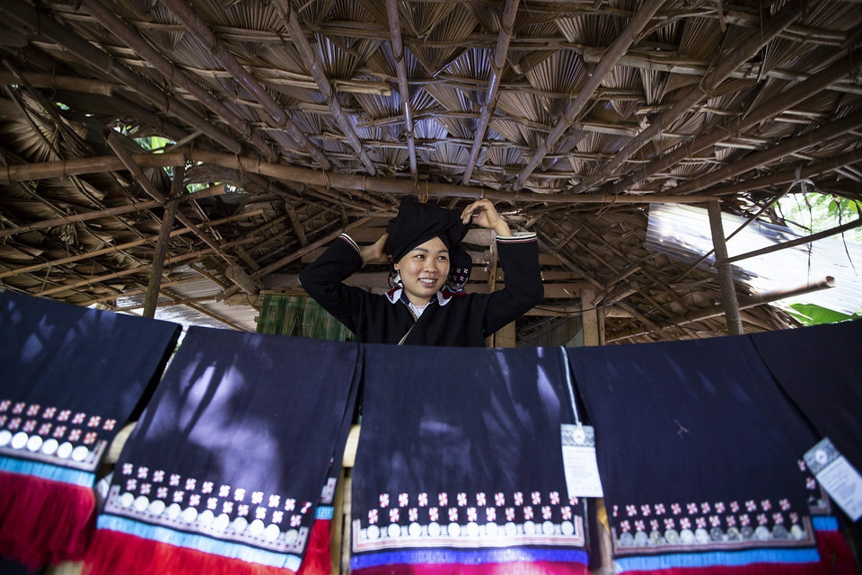 Cô gái Dao Tiền với những tấm khăn trùm đầu thổ cẩm có in họa tiết bằng sáp ong. (Ảnh: Trọng Đạt/TTXVN)