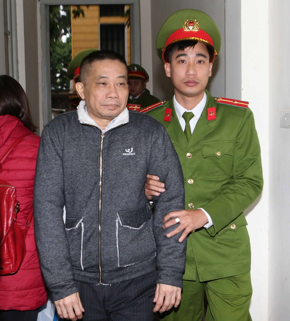 Cảnh sát dẫn giải bị cáo Ninh Văn Quỳnh (sinh năm 1958, nguyên Kế toán trưởng kiêm Trưởng Ban Tài chính Kế toán và Kiểm toán PVN) vào phòng xét xử. (Ảnh: Doãn Tấn/TTXVN)