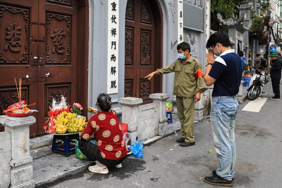 Lực lượng chức năng phường Dịch Vọng, Cầu Giấy nhắc nhở người dân đến làm lễ trước cổng chùa đảm bảo tuân thủ 5K. (Ảnh: Thành Đạt/TTXVN)