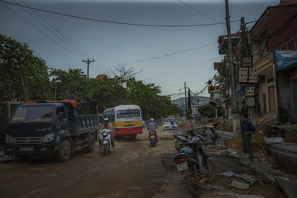 Người dân ngày ngày đi qua đường Hòa Bình nhiều ổ voi, ổ gà đầy bụi trong nỗi lo sợ về an toàn giao thông và sức khỏe. (Ảnh: Trọng Đạt/TTXVN)