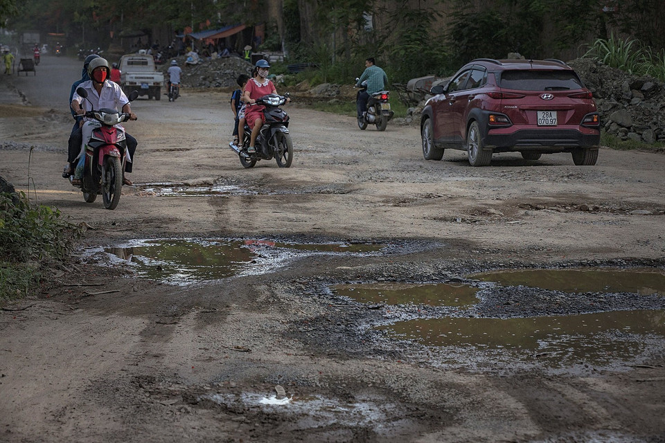 Người dân ngày ngày đi qua đường Hòa Bình nhiều ổ voi, ổ gà đầy bụi trong nỗi lo sợ về an toàn giao thông và sức khỏe. (Ảnh: Trọng Đạt/TTXVN)