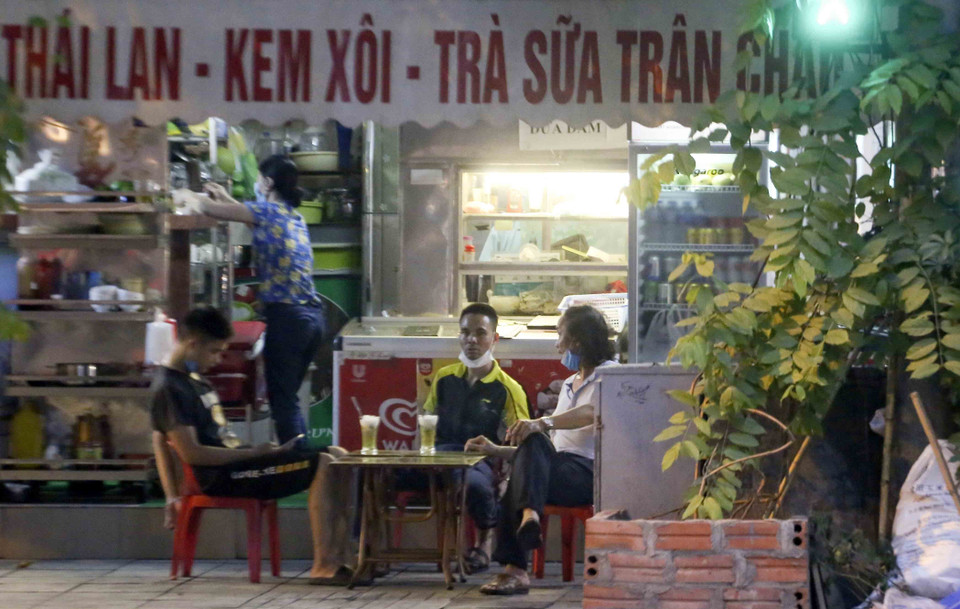 Một số quán cà phê vẫn cho khách ngồi ngoài vỉa hè và đeo khẩu trang không đúng quy cách (ảnh chụp chiều 8/5). (Ảnh: Tuấn Đức/TTXVN)
