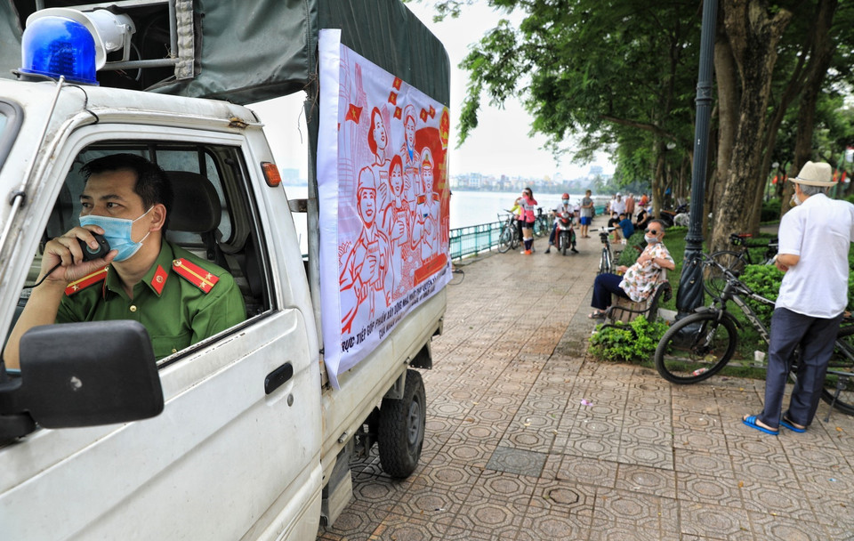 Lực lượng công an phường Thụy Khuê (Ba Đình, Hà Nội) gọi loa nhắc nhở người dân không tụ tập đông người, tập thể dục tại khu vực hồ Tây. (Ảnh: Thành Đạt/TTXVN)