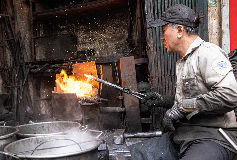 Bằng kinh nghiệm lâu năm trong nghề, ông Hùng chỉ cần quan sát màu lửa là có thể biết nhiệt độ trên sản phẩm. (Ảnh: Hoàng Hiếu/TTXVN)