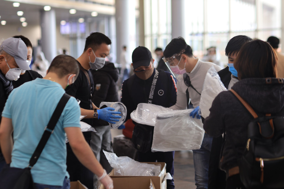 Các nhóm tình nguyện trong cộng đồng người Việt tại Moskva phát tặng quần áo bảo hộ cho các công dân tại sân bay. (Ảnh: Duy Trinh/TTXVN)