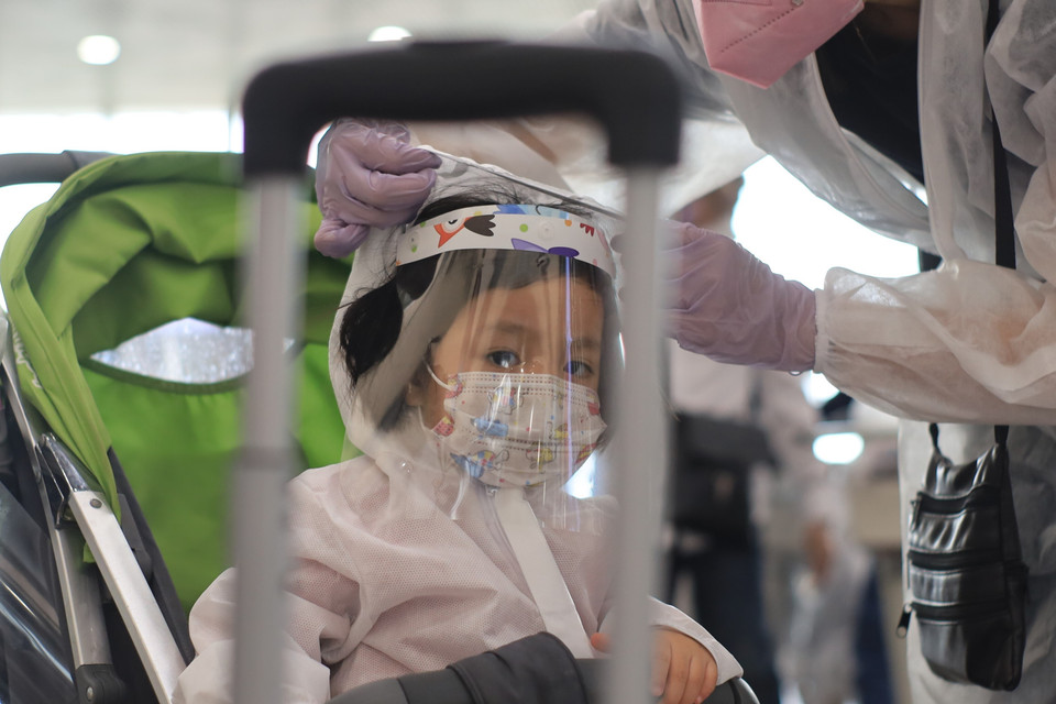 Các em nhỏ được trang bị đồ bảo hộ phòng chống dịch tại ra sân bay. (Ảnh: Trần Hiếu/TTXVN)