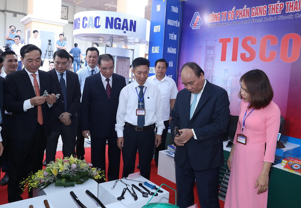 Thủ tướng Nguyễn Xuân Phúc xem gian hàng trưng bày sản phẩm tại hội nghị.(Ảnh: Thống Nhất/TTXVN)