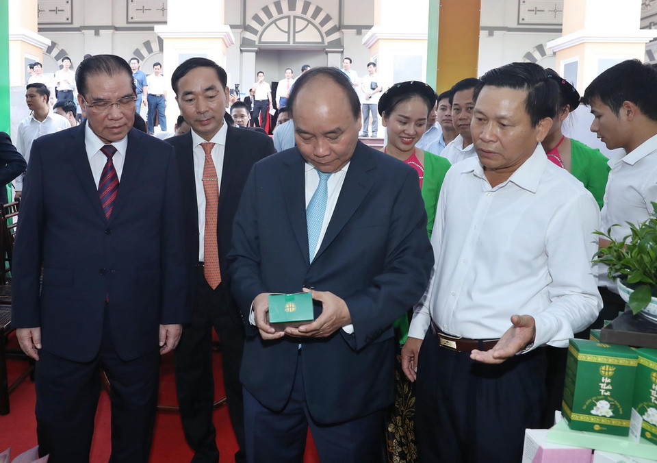 Thủ tướng Nguyễn Xuân Phúc và các đại biểu tham quan gian hàng trưng bày các sản phẩm của tỉnh Thái Nguyên tại hội nghị. (Ảnh: Thống Nhất/TTXVN)
