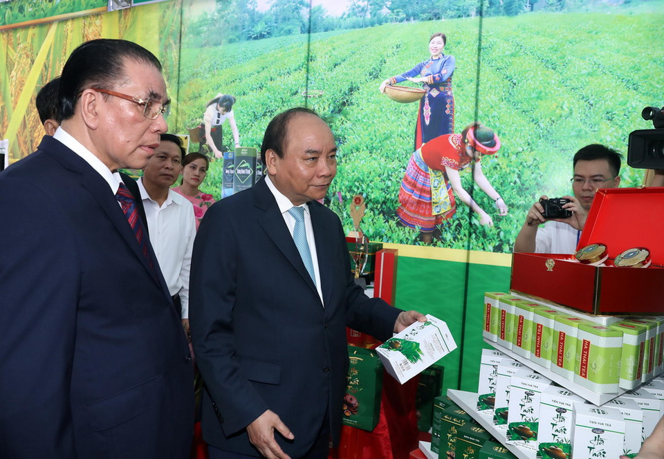 Thủ tướng Nguyễn Xuân Phúc xem gian hàng trưng bày sản phẩm tại hội nghị. (Ảnh: Thống Nhất/TTXVN)