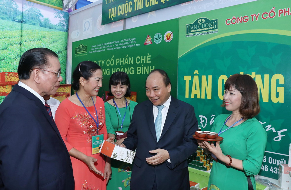 Thủ tướng Nguyễn Xuân Phúc xem gian hàng trưng bày sản phẩm tại hội nghị.(Ảnh: Thống Nhất/TTXVN)