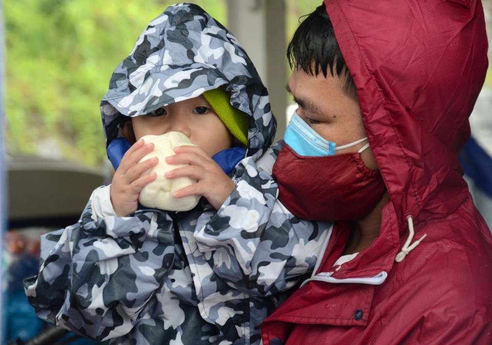 Người về quê tranh thủ nghỉ chân, ăn đồ ăn miễn phí trước khi tiếp tục lên đường. (Ảnh: Quốc Dũng/TTXVN)