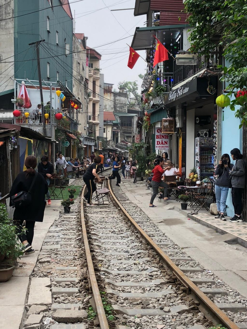  Mỗi khi có chuyến tàu chạy qua, nhiều chủ quán càphê và du khách lại cầm bàn, ghế chạy ra khỏi đường tàu. (Ảnh: Vi Thương-Hải Yến/TTXVN)